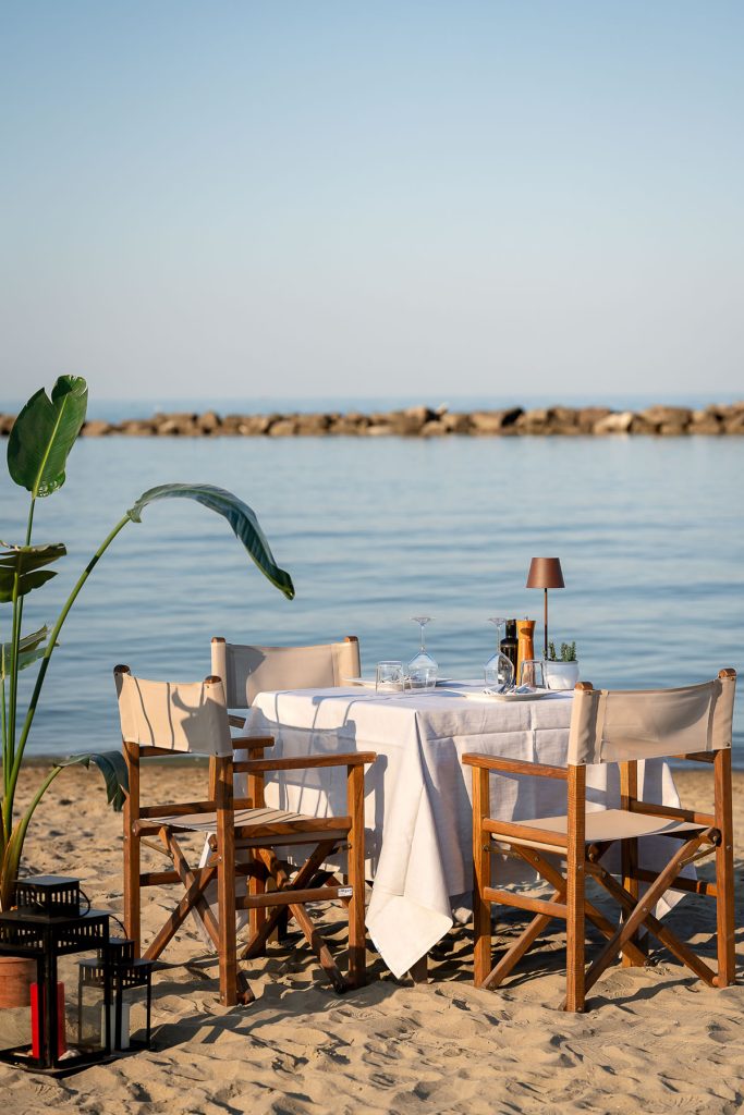 tavolo apparecchiato in spiaggia col mare calmo a due passi