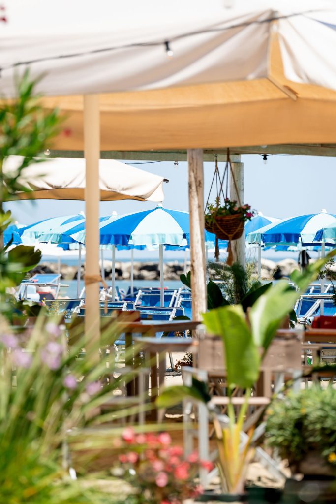 tavoli apparecchiati con la spiaggia a due passi
