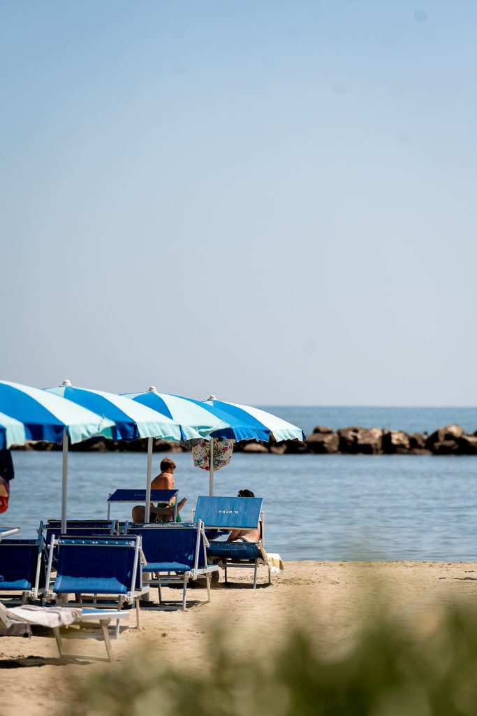 ombrelloni e lettini sulla spiaggia col mare a pochi passi