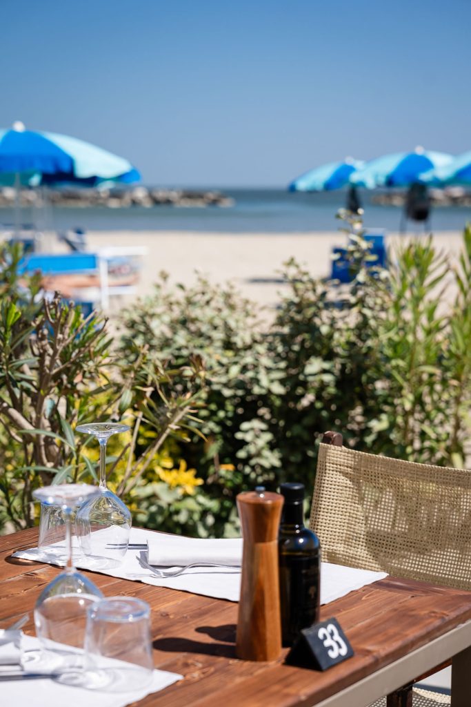 tavolo apparecchiato con sullo sfondo la spiaggia e il mare